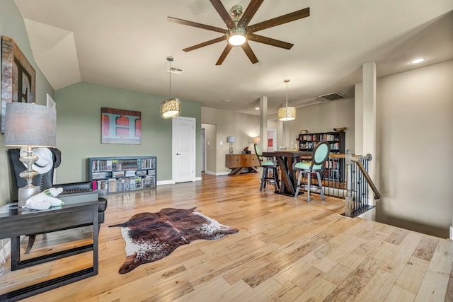 living room with ceiling fan, vaulted ceiling, and light hardwood / wood-style flooring