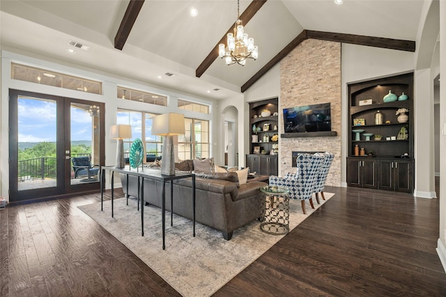 living room with a stone fireplace, a notable chandelier, dark wood-type flooring, built in features, and beamed ceiling