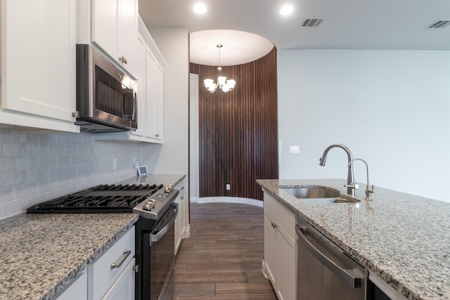 kitchen featuring stainless steel appliances, hanging light fixtures, sink, and white cabinets