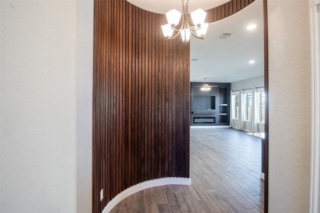 hall featuring wood-type flooring and a chandelier