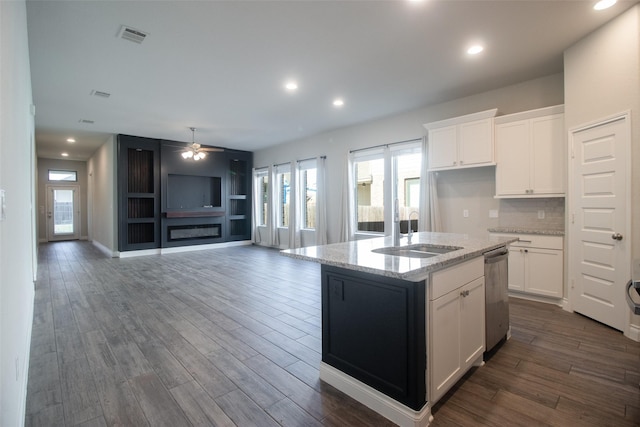 kitchen featuring dishwasher, white cabinetry, sink, and a center island with sink