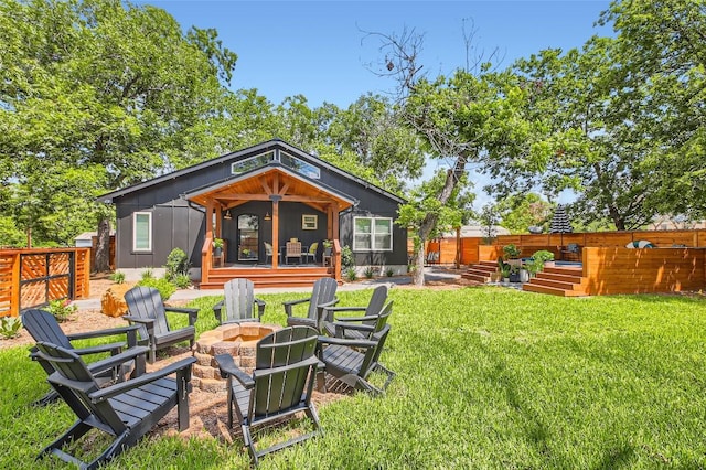 exterior space featuring a wooden deck, a lawn, an outdoor fire pit, and fence