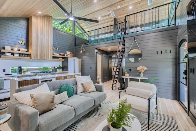 living room featuring wooden ceiling, light wood-style flooring, a ceiling fan, and wood walls