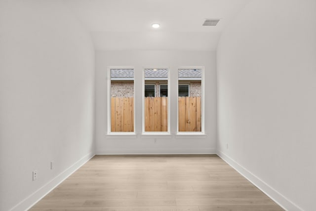 empty room featuring vaulted ceiling and light hardwood / wood-style floors