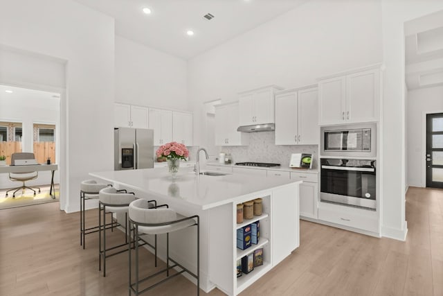 204 Camille St, Leander, TX 78641 - kitchen featuring stainless steel appliances, a towering ceiling, a sink, a kitchen island with sink, and white cabinets