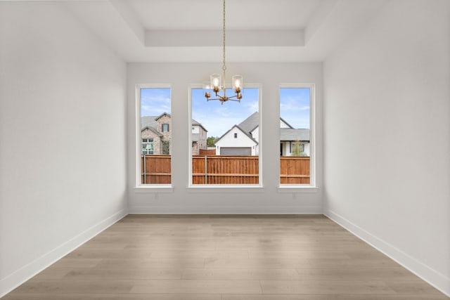 204 Camille St, Leander, TX 78641 - unfurnished dining area featuring a tray ceiling, a chandelier, light wood-type flooring, and baseboards
