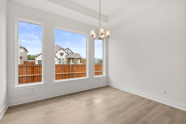 unfurnished dining area with light wood-type flooring and a chandelier