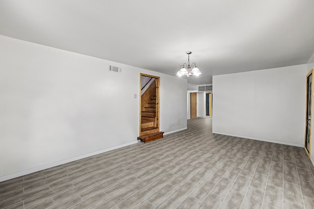 spare room featuring light hardwood / wood-style flooring and a chandelier