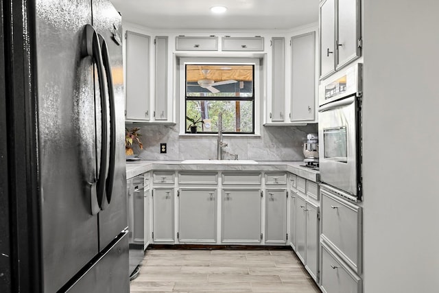 kitchen featuring white cabinets, light hardwood / wood-style flooring, stainless steel appliances, sink, and decorative backsplash