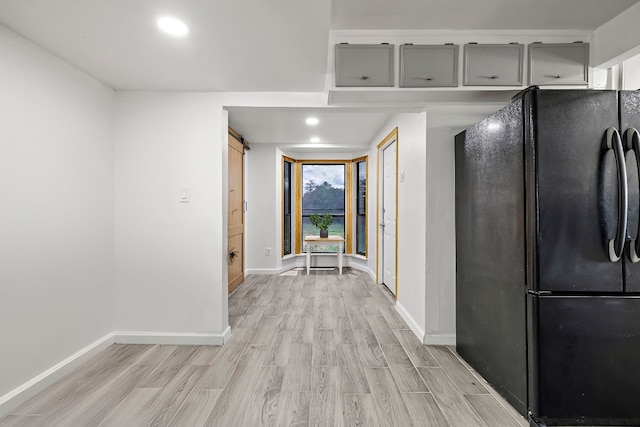 interior space featuring light hardwood / wood-style flooring, gray cabinetry, and black fridge