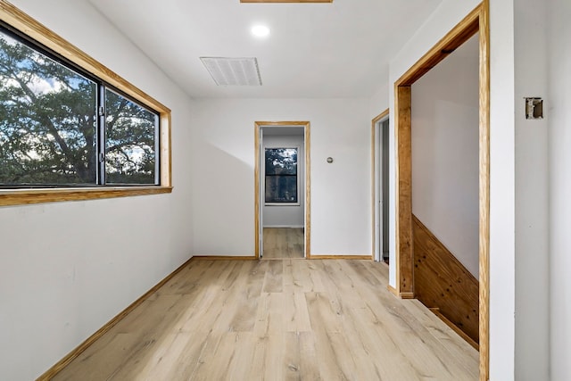 hall with a wealth of natural light and light hardwood / wood-style floors