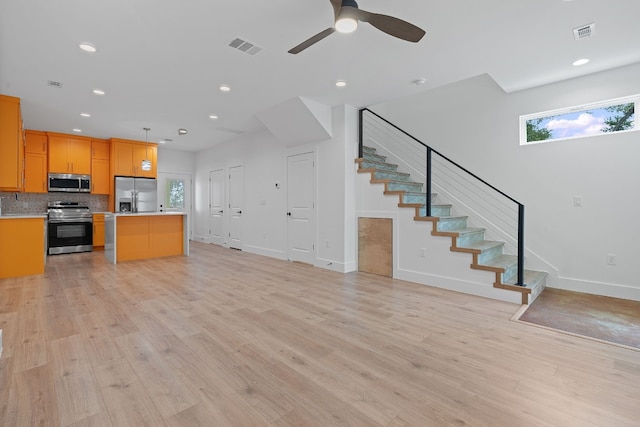 kitchen featuring a kitchen island, visible vents, open floor plan, light countertops, and appliances with stainless steel finishes