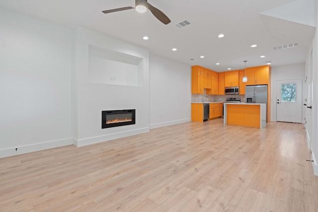 kitchen featuring tasteful backsplash, decorative light fixtures, appliances with stainless steel finishes, a kitchen island, and ceiling fan