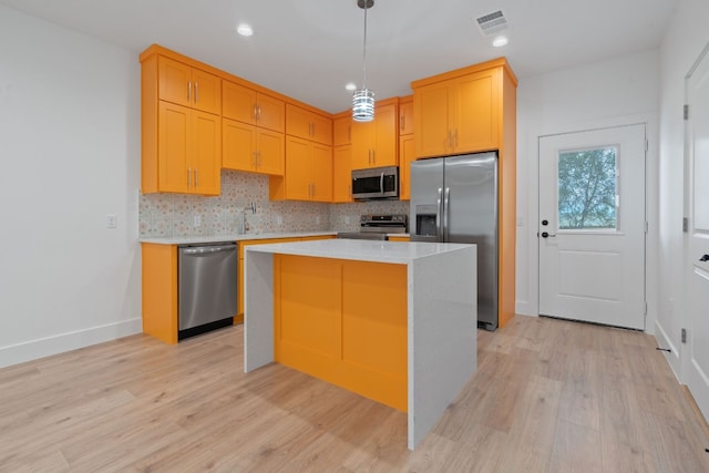 kitchen featuring a center island, decorative light fixtures, stainless steel appliances, light countertops, and visible vents