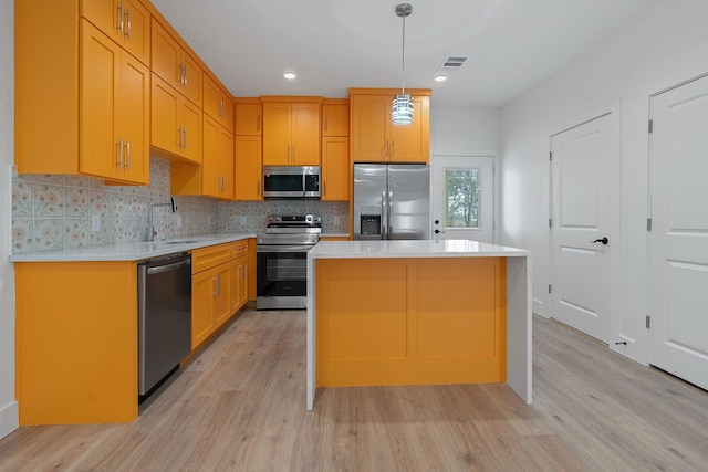 kitchen featuring pendant lighting, stainless steel appliances, light countertops, a kitchen island, and a sink