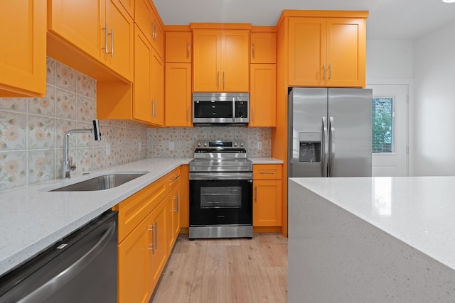 kitchen featuring stainless steel appliances, sink, backsplash, and light stone counters