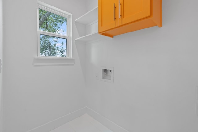 clothes washing area with cabinet space, baseboards, and washer hookup