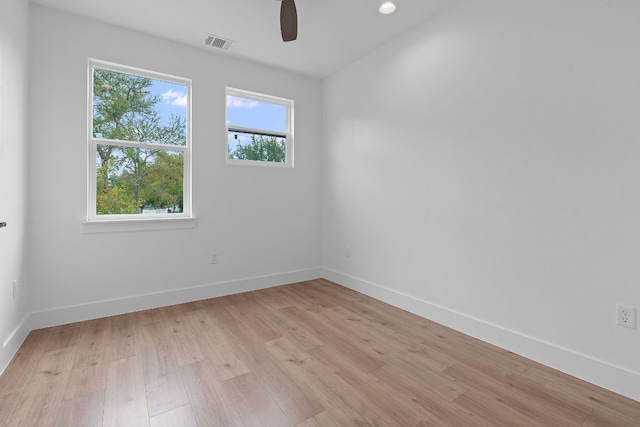 empty room with light wood-type flooring, visible vents, and baseboards