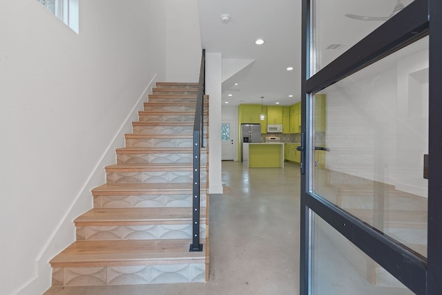 stairway with finished concrete flooring and recessed lighting