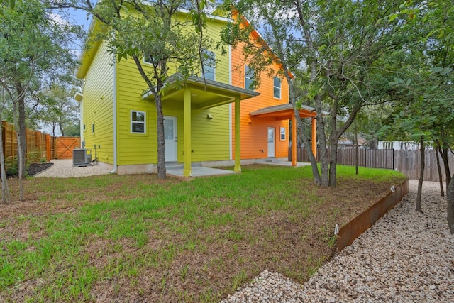 rear view of house featuring a fenced backyard, a lawn, and cooling unit