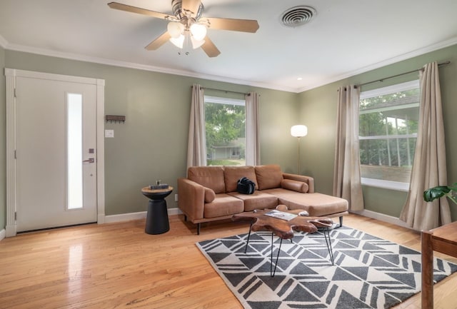 living room featuring plenty of natural light, light hardwood / wood-style floors, crown molding, and ceiling fan