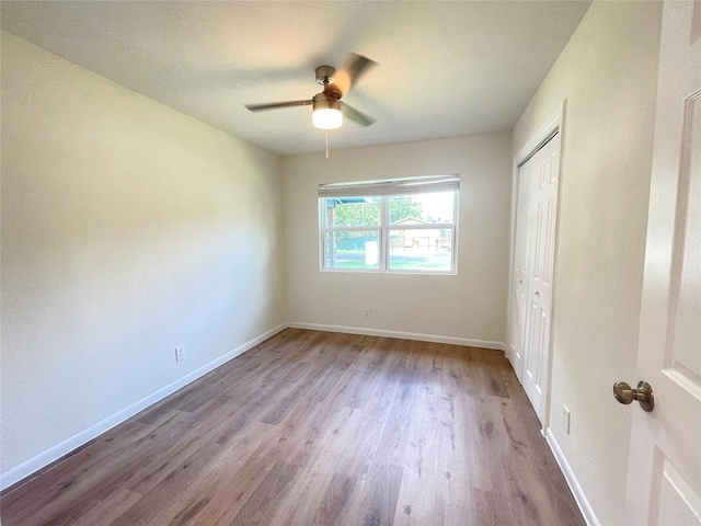 unfurnished bedroom featuring light hardwood / wood-style flooring, ceiling fan, and a closet