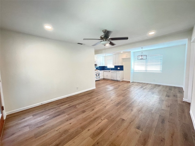 unfurnished living room with hardwood / wood-style floors and ceiling fan with notable chandelier