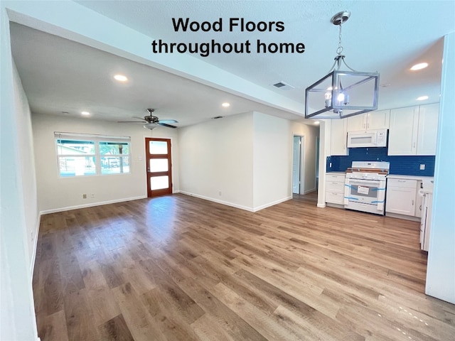 kitchen featuring white appliances, white cabinetry, decorative light fixtures, and light hardwood / wood-style flooring