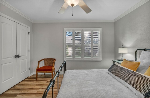 bedroom featuring crown molding, light hardwood / wood-style flooring, ceiling fan, and a closet