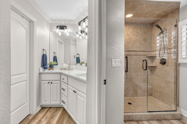 bathroom featuring crown molding, vanity, wood-type flooring, and a shower with door