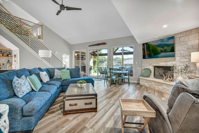 living room with a fireplace, light wood-type flooring, high vaulted ceiling, and ceiling fan