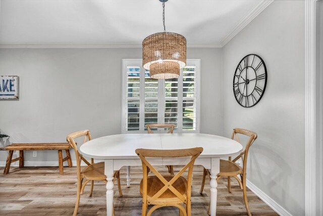 dining space featuring crown molding, an inviting chandelier, and light wood-type flooring