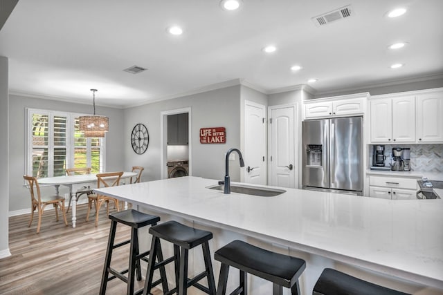 kitchen with white cabinetry, light hardwood / wood-style flooring, light stone counters, sink, and stainless steel refrigerator with ice dispenser