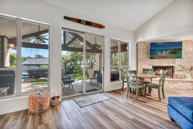 doorway featuring lofted ceiling, plenty of natural light, a stone fireplace, and hardwood / wood-style floors