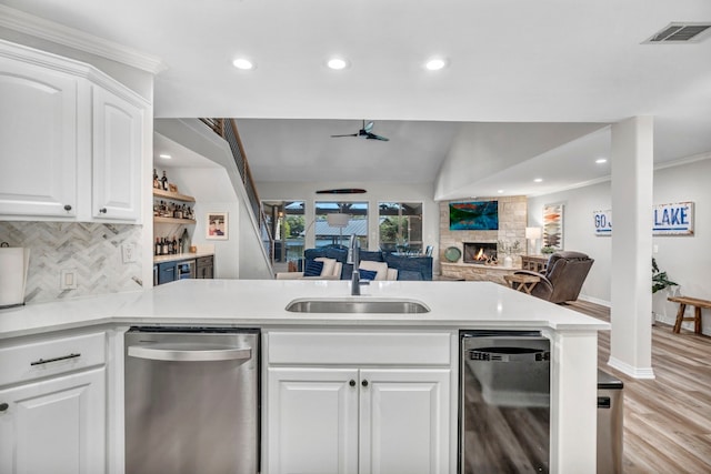 kitchen with white cabinets, a fireplace, kitchen peninsula, ceiling fan, and stainless steel dishwasher