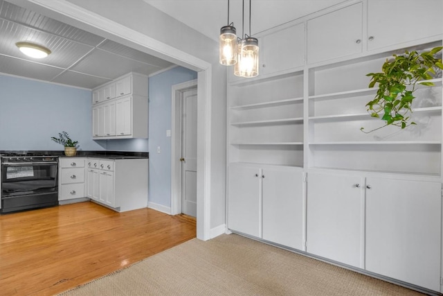 kitchen with decorative light fixtures, light wood-type flooring, gas stove, and white cabinets