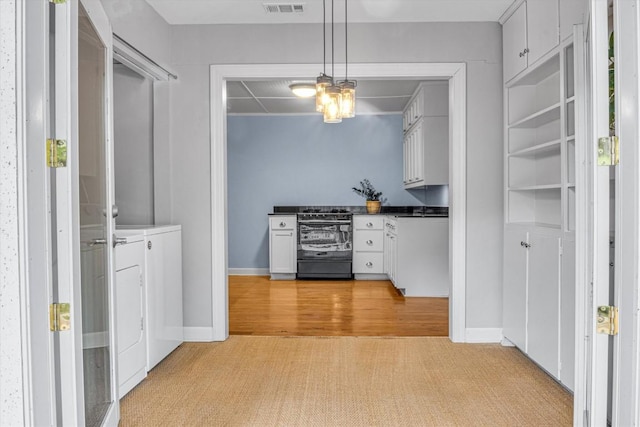 kitchen with white cabinetry, decorative light fixtures, black gas range, independent washer and dryer, and light carpet