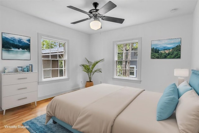 bedroom with light wood-type flooring, ceiling fan, and multiple windows