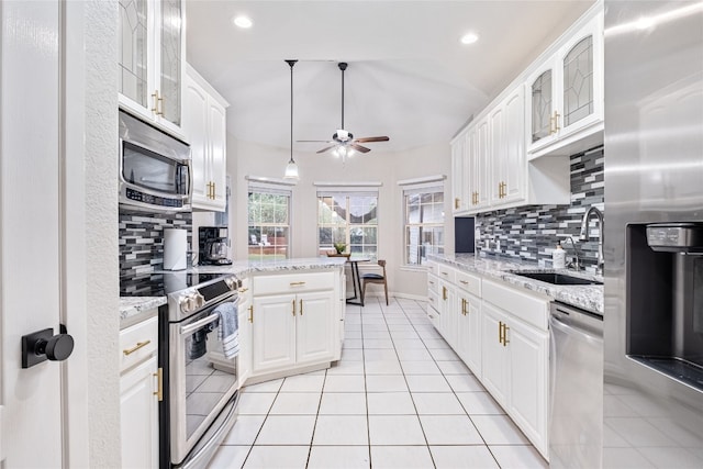 kitchen featuring light stone countertops, appliances with stainless steel finishes, sink, white cabinetry, and ceiling fan