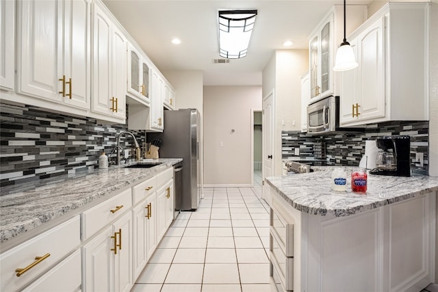 kitchen featuring white cabinets, hanging light fixtures, light stone countertops, stainless steel appliances, and sink