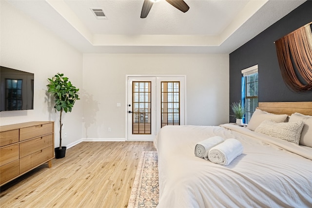 bedroom featuring light wood-type flooring, a tray ceiling, ceiling fan, and access to exterior