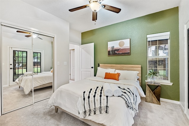 bedroom featuring multiple windows, a closet, ceiling fan, and light colored carpet