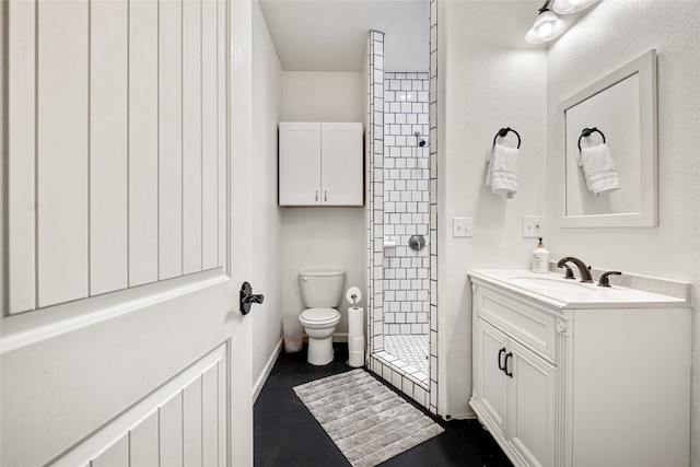 bathroom featuring tiled shower, vanity, and toilet