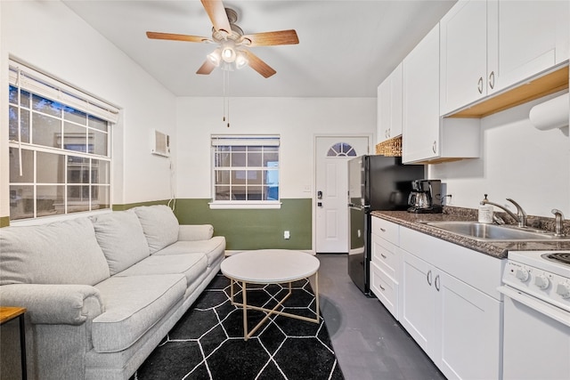 kitchen with white cabinetry, sink, white range, black fridge, and ceiling fan