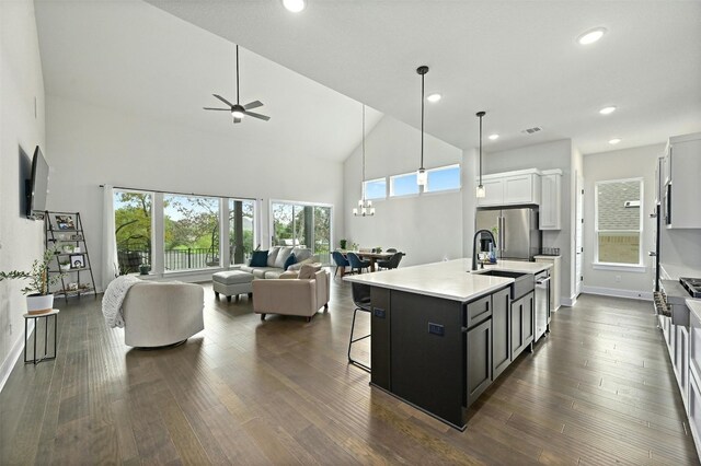 kitchen featuring ceiling fan with notable chandelier, dark hardwood / wood-style floors, a breakfast bar area, a center island with sink, and white cabinets