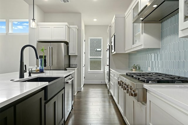 kitchen with hanging light fixtures, range hood, dark hardwood / wood-style floors, appliances with stainless steel finishes, and white cabinets