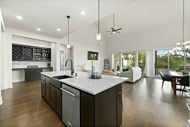 kitchen with ceiling fan with notable chandelier, dark hardwood / wood-style flooring, sink, a center island with sink, and stainless steel dishwasher