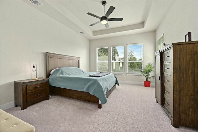 bedroom featuring ceiling fan, light colored carpet, and a raised ceiling