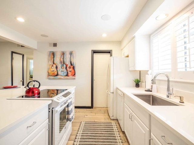 kitchen featuring white cabinets, white appliances, light hardwood / wood-style floors, and sink