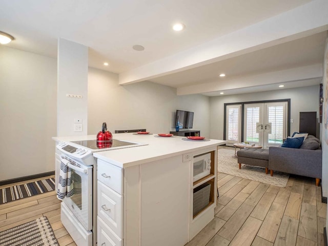 kitchen with light wood-type flooring, white appliances, white cabinetry, french doors, and beam ceiling